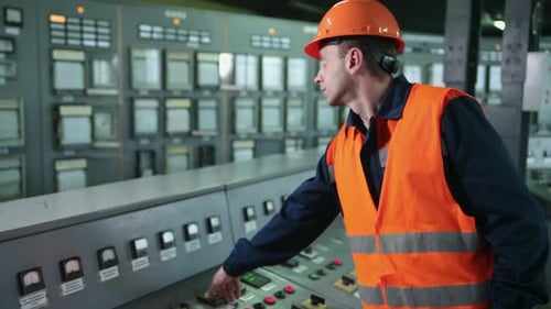 Male operating machinery at factory control panel