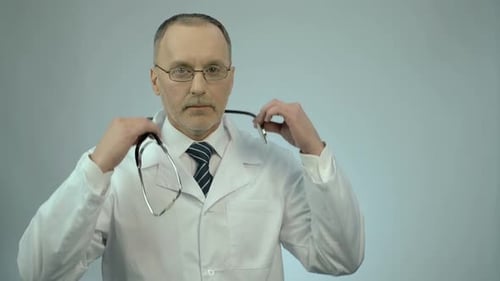 Man Putting on Stethoscope in Front of Gray Backdrop