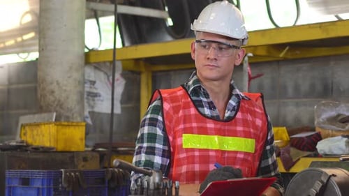 Engineer foreman with repair checklist working repair on machine at the factory