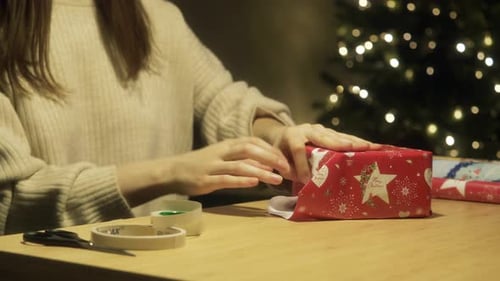 Woman Wrapping Christmas Present at Night