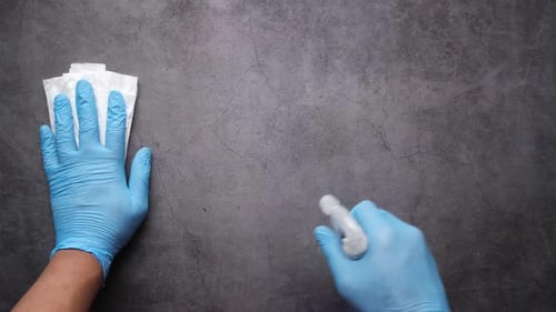 Hands in Gloves Clean Surface With Spray and Wipes