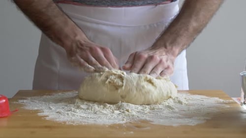 Baker Kneading Dough on a Wooden Cutting Board