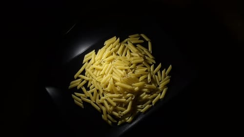 Uncooked Penne Pasta on a Black Plate