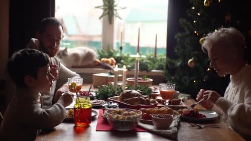 Side View of Happy Caucasian Young Family Enjoying at Festive Christmas Table During Holiday Family