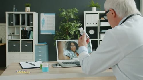 Medic Talking To Sick African American Girl Online Using Computer From Clinic Office