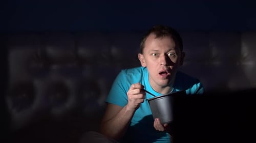 удивленный человек смотрит телевизор в темноте