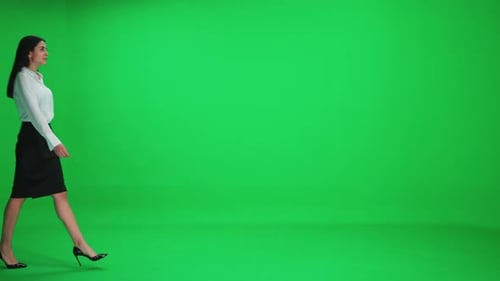 Young Businesswoman in a Suit Walks on a Green Background a Chromakey Template