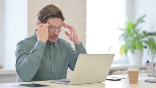 Man at Laptop Experiencing Headache in Office