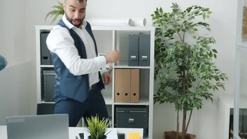 Cheerful Entrepreneur Working with Laptop Then Dancing Doing Highfive with Colleagues Celebrating