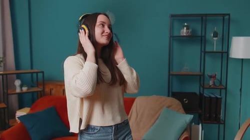 Smiling Woman Dancing with Yellow Headphones at Home