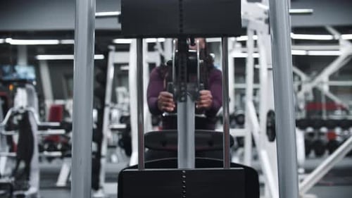 Eine schwarze Frau, die in einem Fitnessstudio trainiert, trainiert Hände an einem Trainingsgerät mit Gewichten