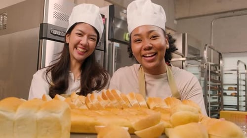 Smiling bakers with fresh bread in commercial kitchen