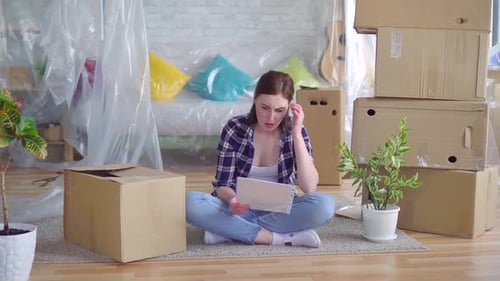Tired Young Woman Among the Boxes To Movereads the Documents for Eviction