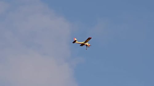 Small Airplane Flying Across Blue and White Sky