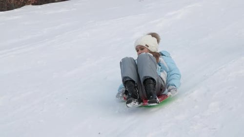 Pretty Girl Toboganning Down Snowy Hill