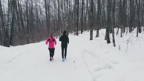 Man and Woman in the Winter Running Through the Park in Slow Motion.