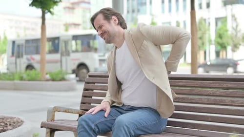 Man Sitting on Bench Experiencing Back Pain