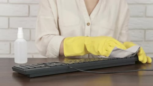 Woman Cleaning Computer Keyboard With Rag and Spray
