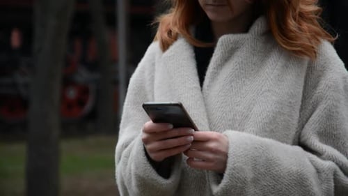 Chica con un abrigo escribe un mensaje