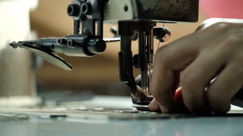 Close-Up Of Tailor Working On Sewing Machine in leather factory background