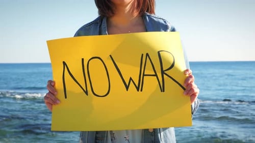 Woman on Beach Holds "No War" Sign