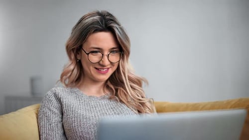 Young Woman Using Laptop on Sofa Indoors