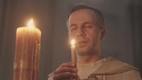 Clergyman with Candle Praying in Church