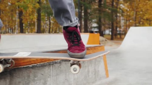 Skater Practicing in the Autumn Concrete Skate Park Making Tricks and Rides in Ramp