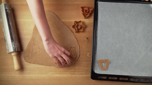 Making shapes from gingerbread dough on a wooden table and placing them to baking tin topdown video