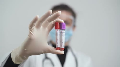 Weibliche Hand hält Blutbehälter und Vacutainer-Röhrchen im Labor für Coronavirus-Tests