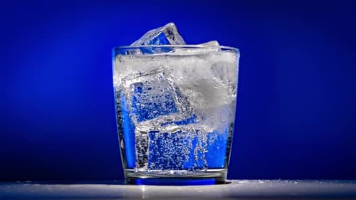 Sparkling Water Poured into Glass with Ice Cubes