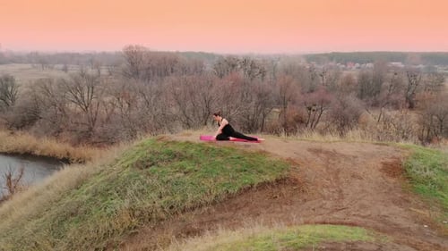 Junge Frau macht Yoga in ruhiger Landschaft