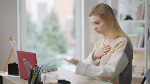 Side View of Concentrated Young Woman Using Sign Language Watching Video Lesson Online on Laptop