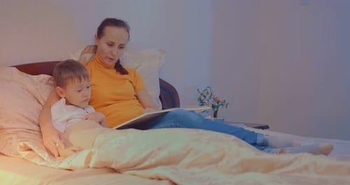 Woman Reading to Child in Bed at Night