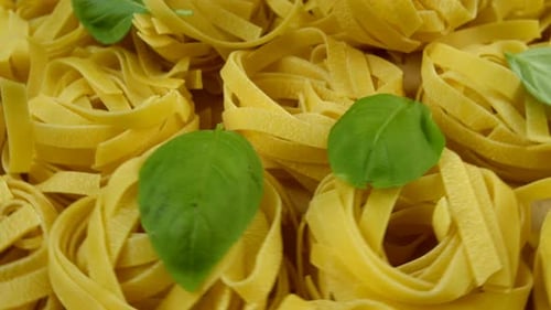 Lots of Dry Tagliatelle Pasta Garnished with Basil Leaves Rotate of Circle Counterclockwise