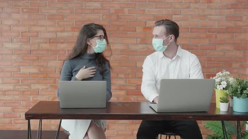 Young american business man and woman in face mask working on laptop computer at office.