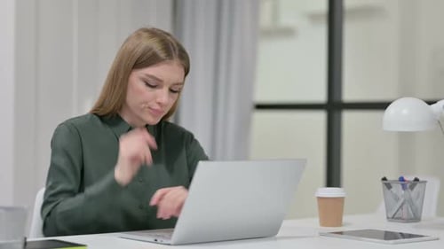 Thoughtful Woman Typing at Desk with Laptop