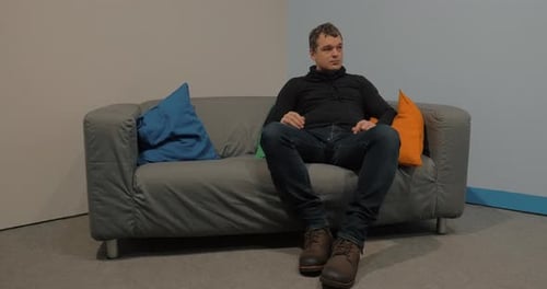 Homem sentado no sofá no saguão e esperando