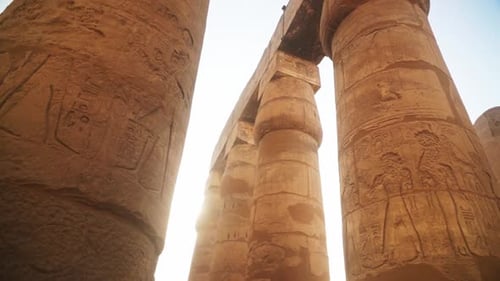 Massive pillars with intricate carved images and hieroglyphs in the Kamak Temple, Luxor, Egypt.
Sun