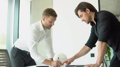 Engineer and Architect Reviewing Office Blueprints and Technical Drawings