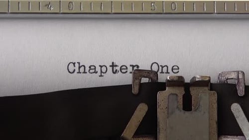 Typing phrase Chapter One on retro typewriter. Close up.