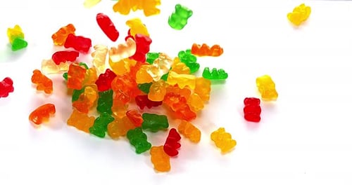 Colorful Gummy Bears Falling on a White Surface