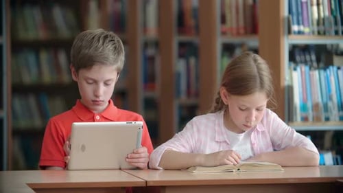 Focused Children Studying with Tablet and Book in Library