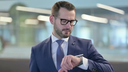 Man in Suit Looking at Watch in Office