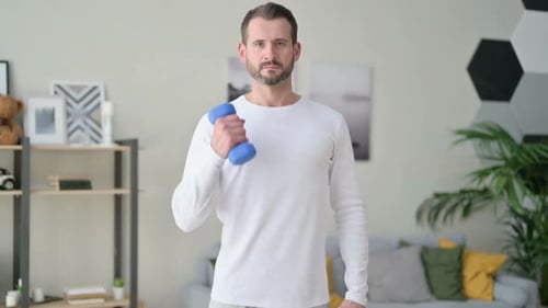 Man Lifting Dumbbell Doing Bicep Curl Exercise Indoors
