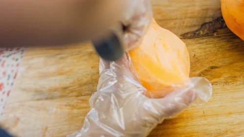 Gloved Hands Peeling a Sweet Potato