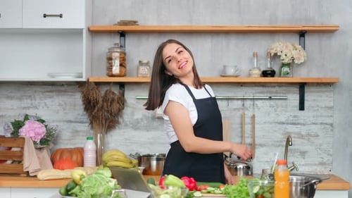 Smiling Woman in Kitchen near Fresh Vegetables