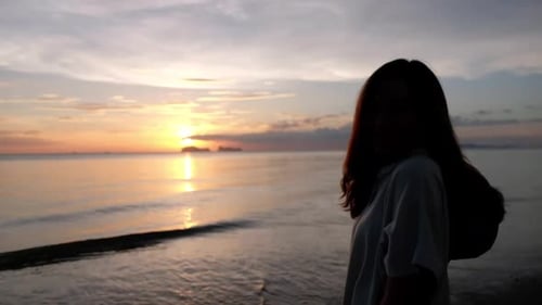 Eine Frau, die vor Sonnenuntergang am Strand spaziert