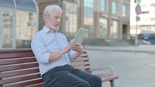 Senior Man Using Tablet on Bench in City