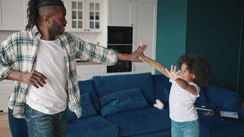Happy African American Girl Dancing with Her Positive Father at Home Having Fun Together